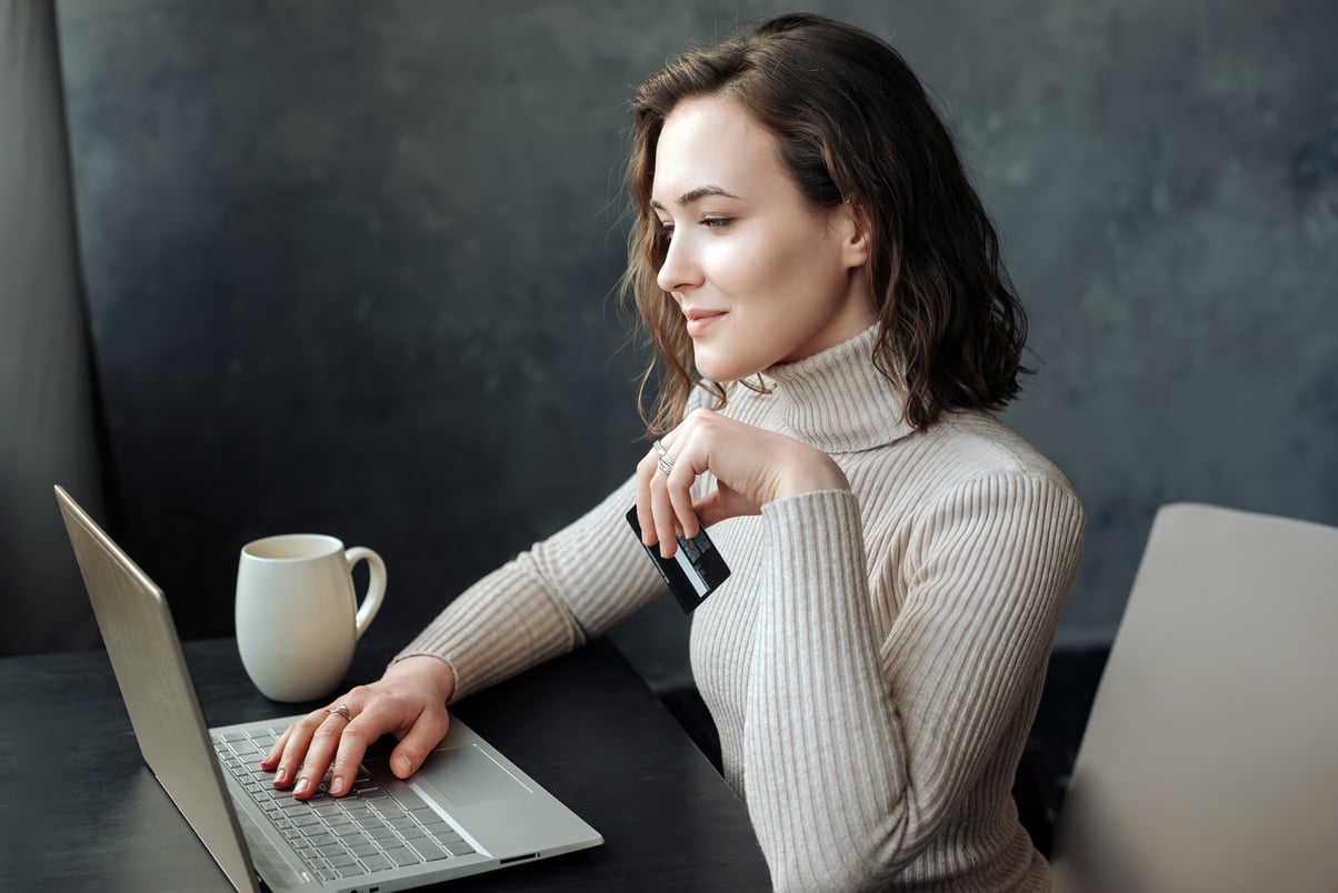 Young Woman Shopping Online: Holding Credit Card and Using Laptop for E-Commerce Transactions